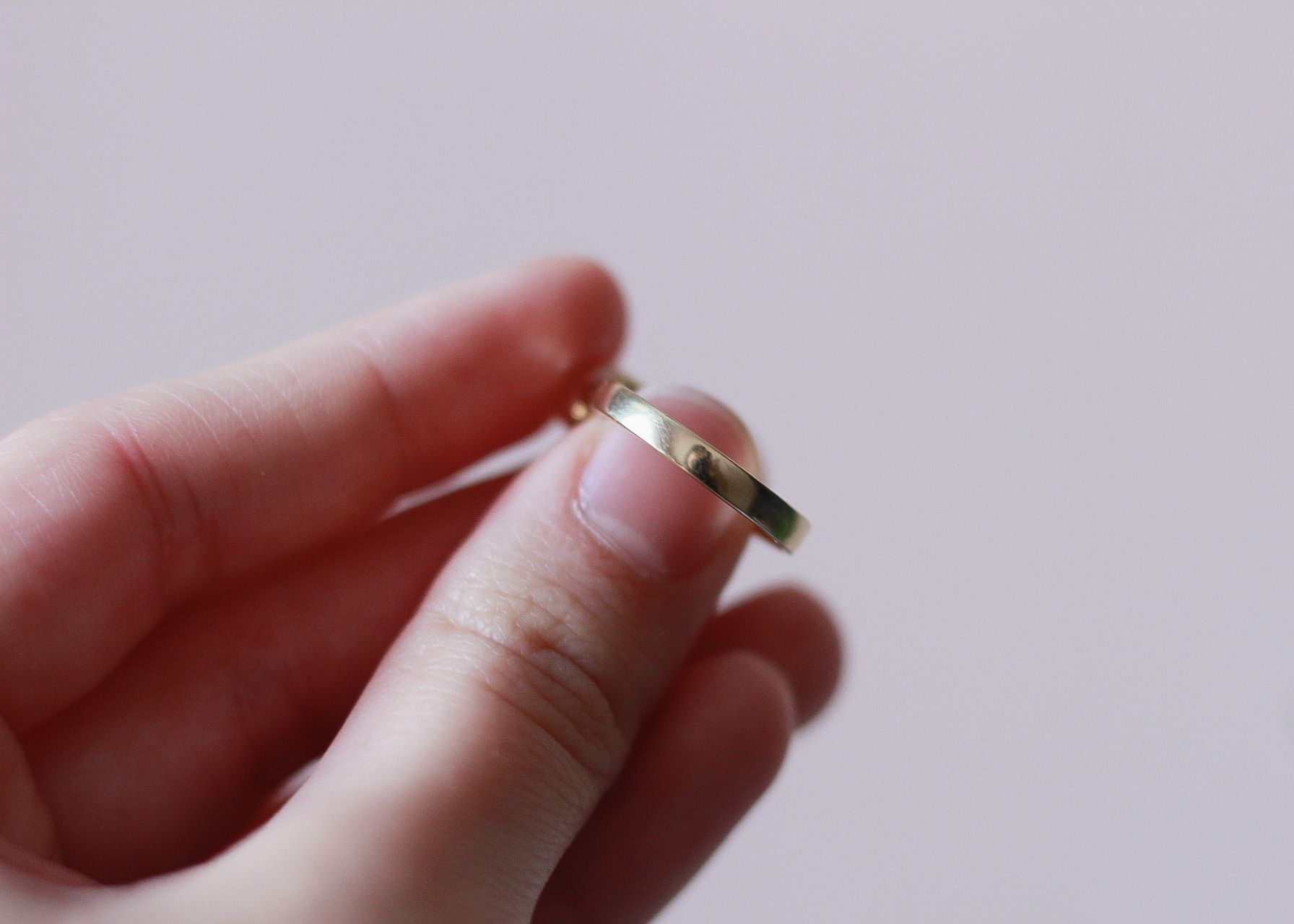 image of a left hand showing the smooth, plain back of a gold ring